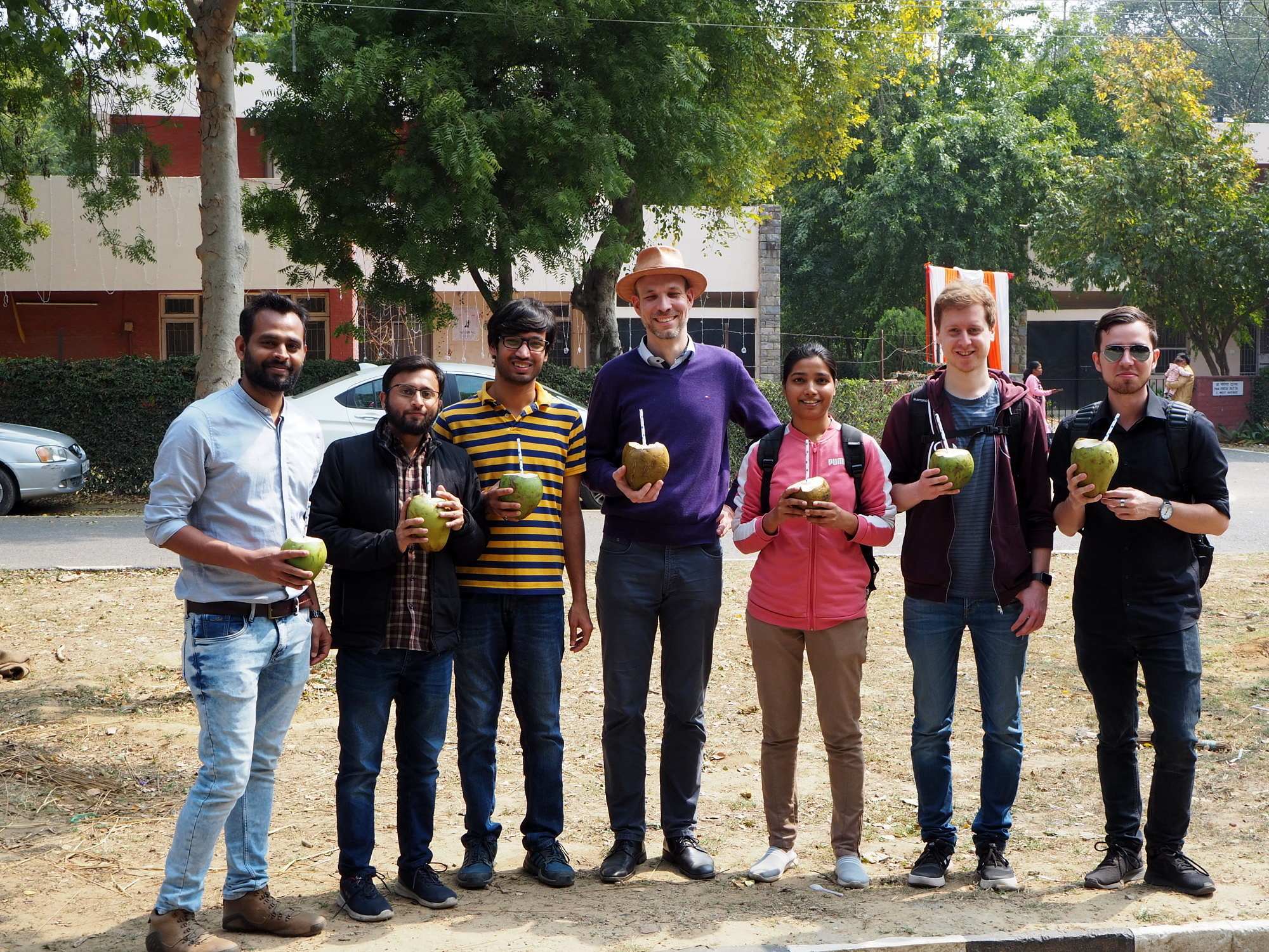 Group photo of seven researchers from the technical faculties at Friedrich-Alexander-Universität Erlangen-Nürnberg and the Indian Institute of Technology Delhi drinking coconut milk in Delhi.
